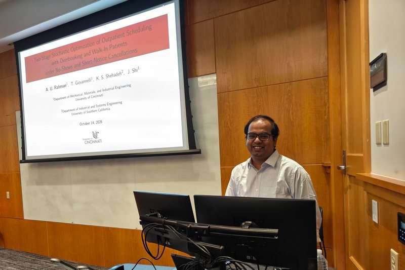Amanat Ur Rahman at the lectern beside the title slide of his talk on two-stage stochastic optimization of outpatient scheduling.